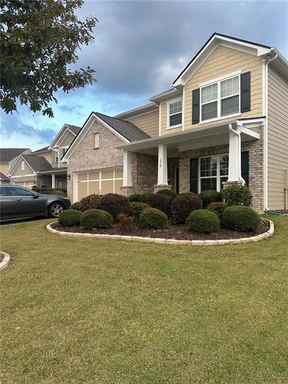 View of front of home featuring a front yard, brick siding, and covered porch