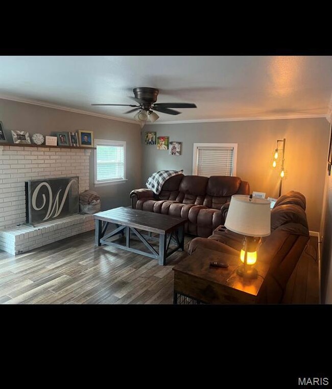 Living area featuring ornamental molding, a fireplace, wood finished floors, and ceiling fan