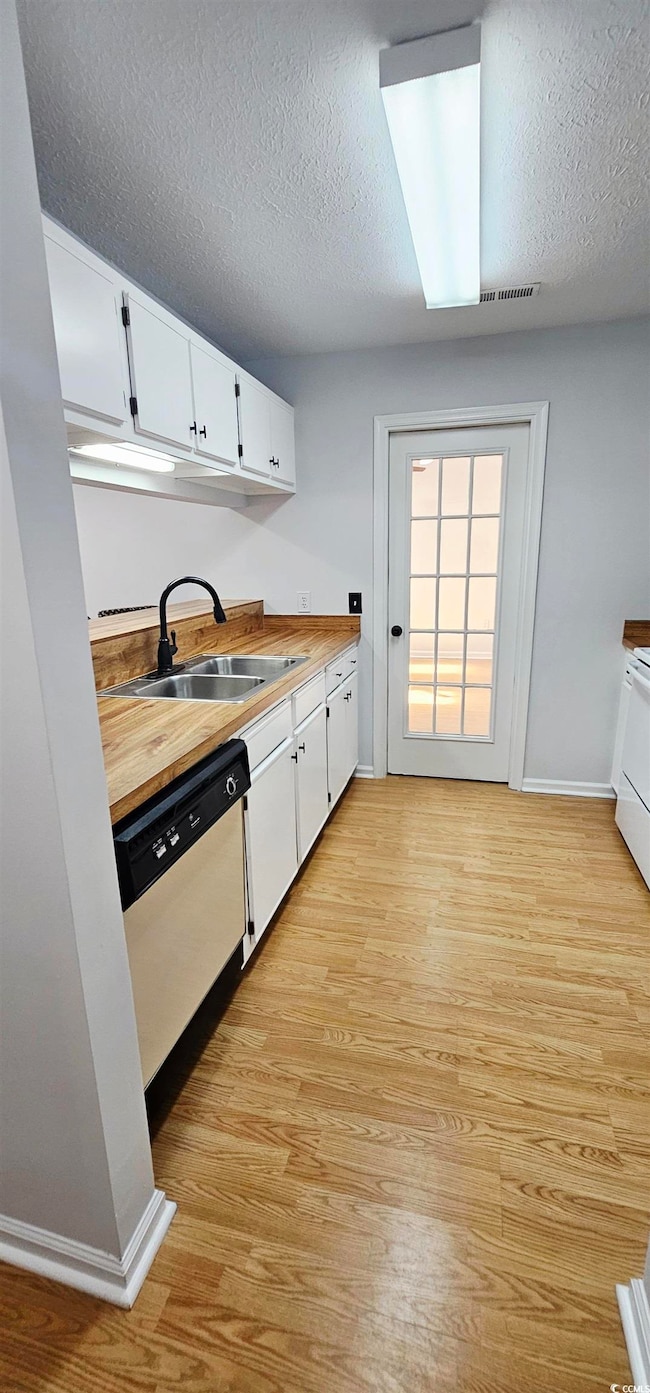 Kitchen with white cabinets, a textured ceiling, light wood finished floors, dishwasher, and white range oven