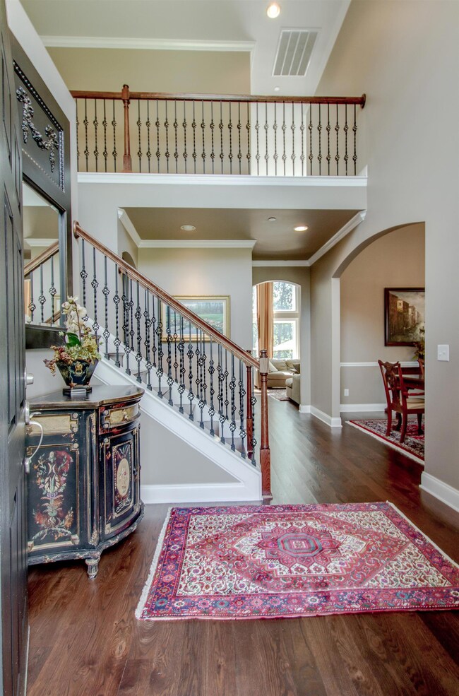 Dramatic two-story entry foyer.  The beautiful staircase features hardwood treads, wrought iron basket weave spindles which lead up the stairs and continue through the hallway and overlook into the Family Room.
