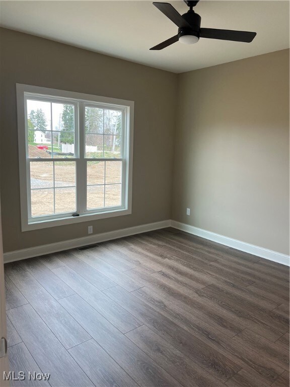 Unfurnished room featuring dark wood-style flooring and ceiling fan