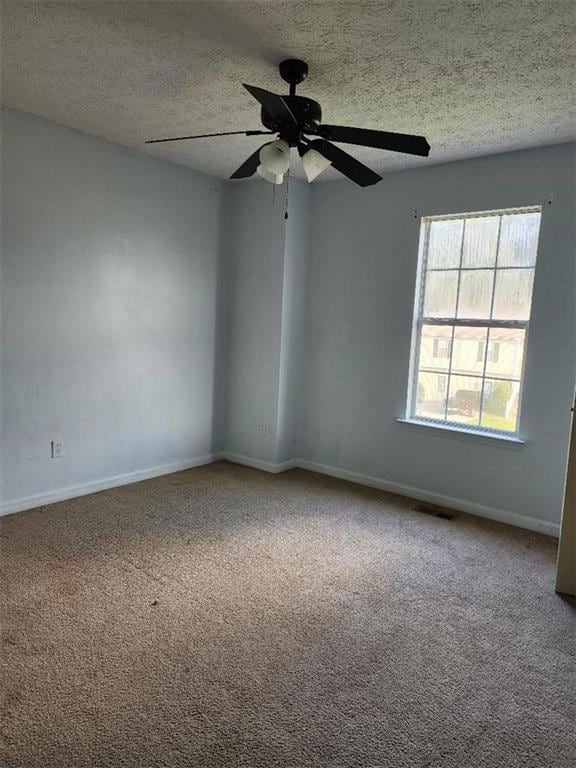Carpeted empty room featuring a textured ceiling and a ceiling fan