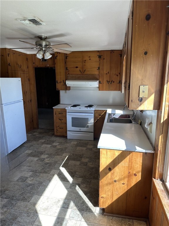 Kitchen featuring white appliances, extractor fan, ceiling fan, sink, and wood walls