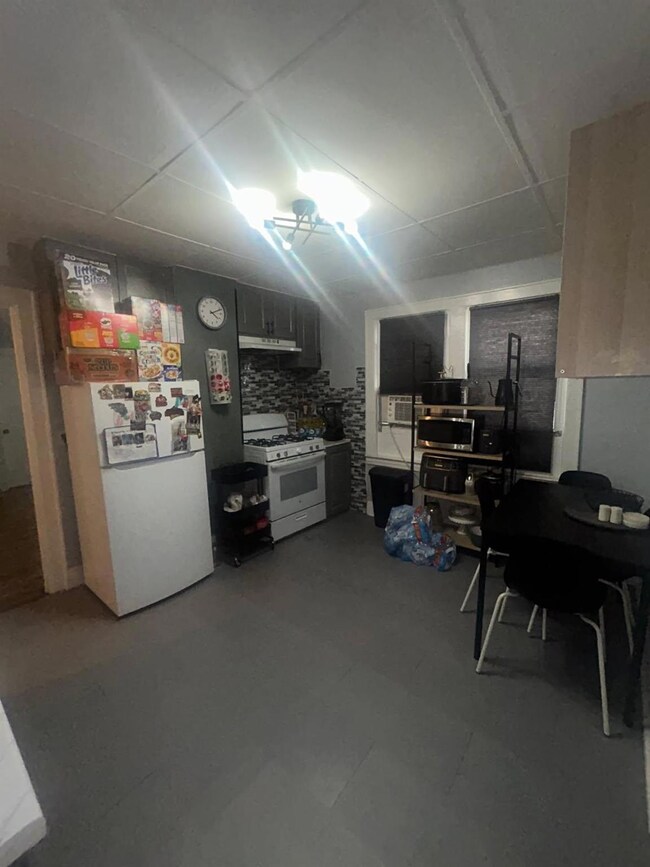 Kitchen with white appliances, tile patterned floors, and under cabinet range hood