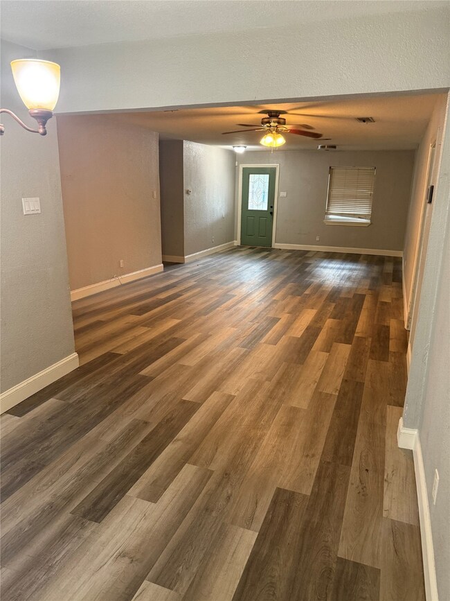 Unfurnished living room featuring dark wood finished floors and a ceiling fan