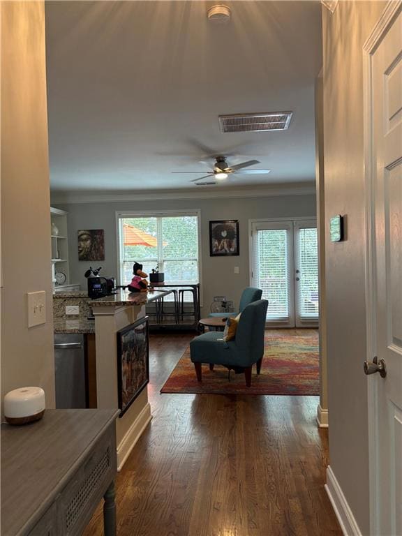 Living area with dark wood-type flooring, plenty of natural light, ornamental molding, and a ceiling fan