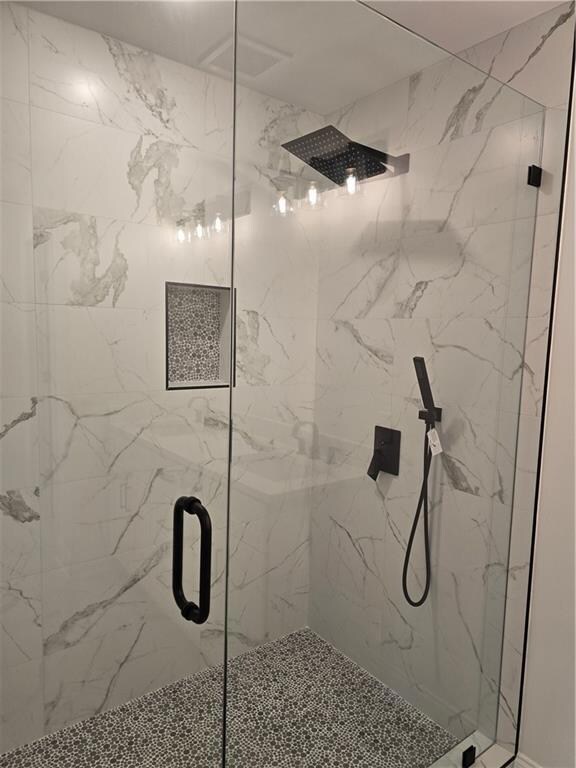 Full bathroom with a marble finish shower