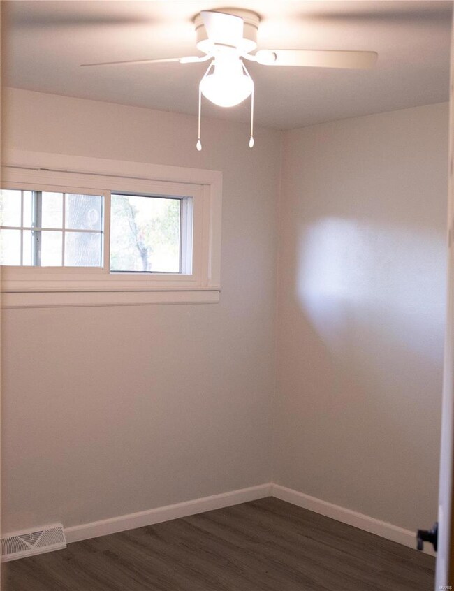 Empty room featuring dark wood-type flooring and ceiling fan