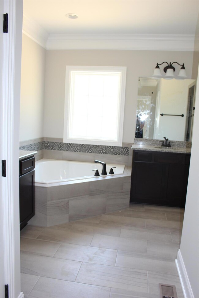 Master bath suite has corner jetted tub with ceramic surround; his and her vanities, separate ceramic shower and 12 x 24 tiles.
