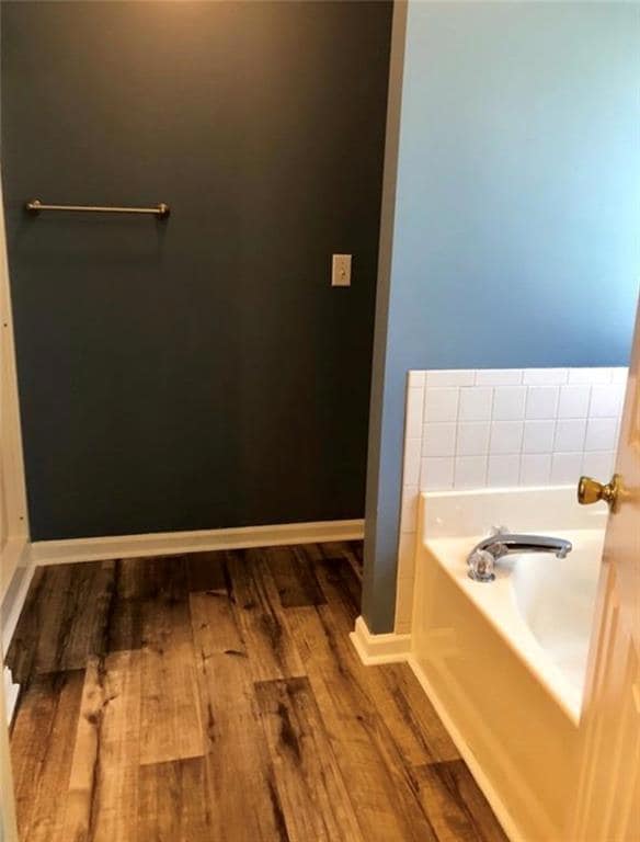 Full bath with a garden tub and wood finished floors