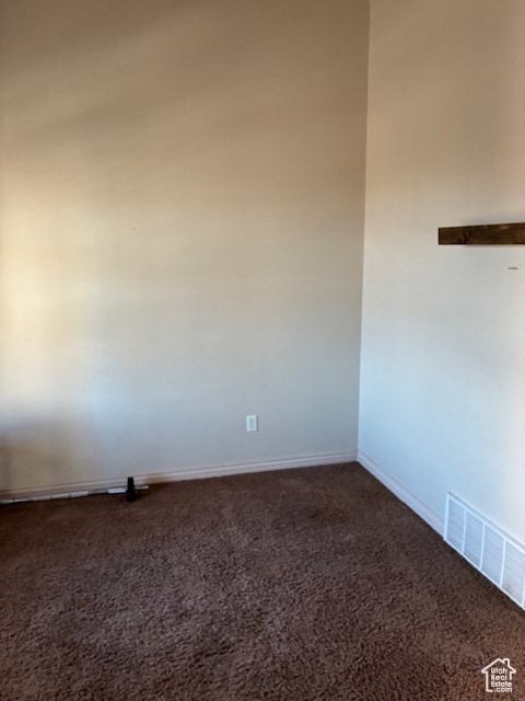 Unfurnished room featuring dark carpet and baseboards
