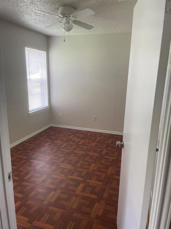 Empty room featuring ceiling fan and a textured c