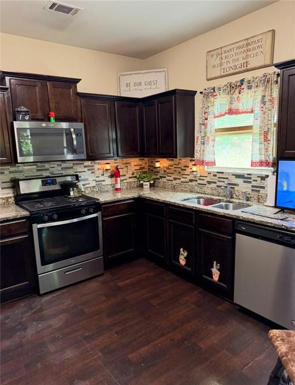 Kitchen featuring stainless steel appliances, tasteful backsplash, light stone countertops, dark wood-style floors, and dark brown cabinetry