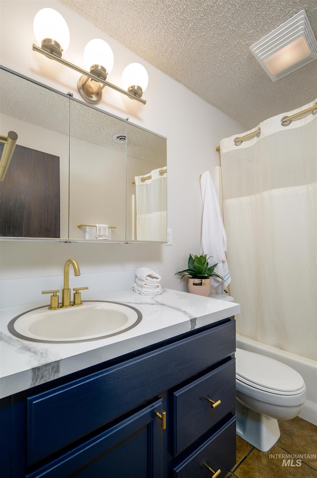 Full bath with a textured ceiling, vanity, tile patterned floors, and shower / bath combo with shower curtain