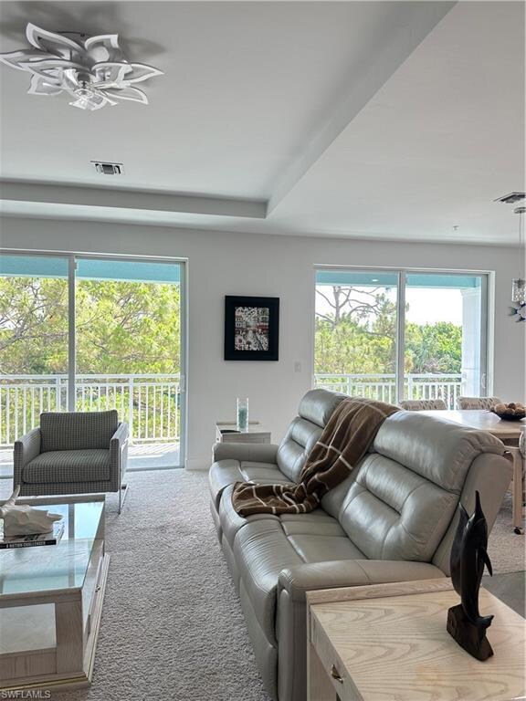 Carpeted living area with healthy amount of natural light and ceiling fan
