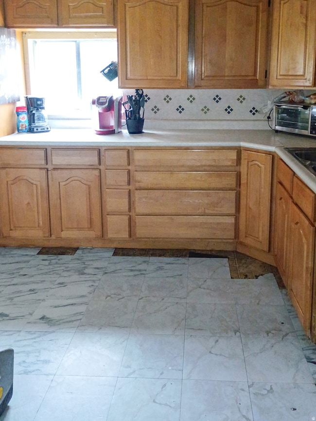 Kitchen featuring light countertops, brown cabinetry, and light marble finish flooring