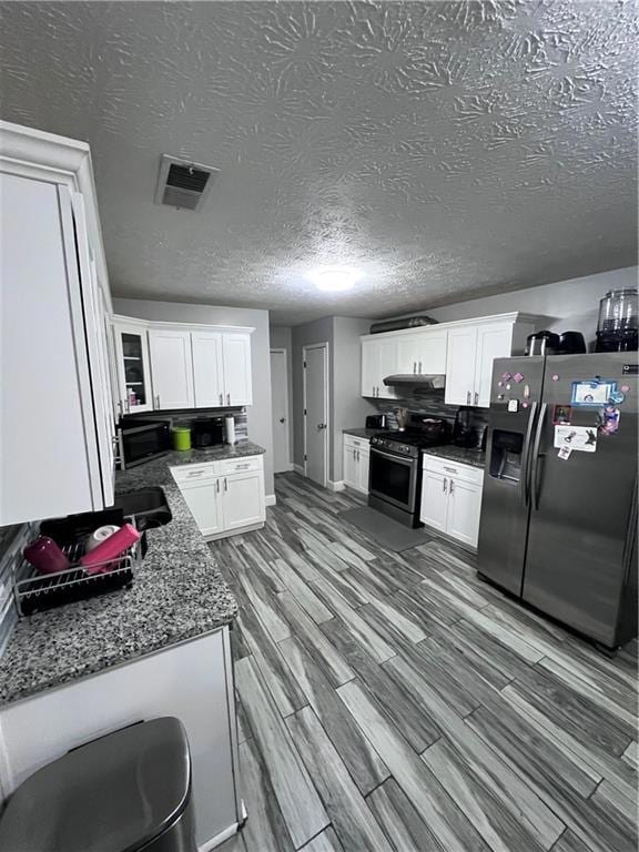 Kitchen with dark stone counters, white cabinets, 