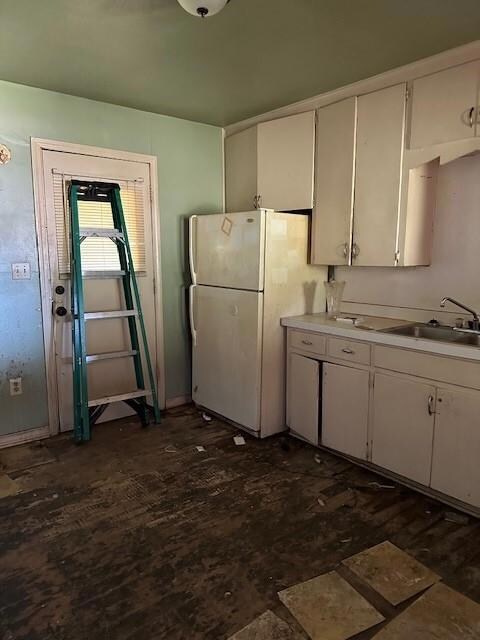 Kitchen with white cabinets, sink, and white fridge