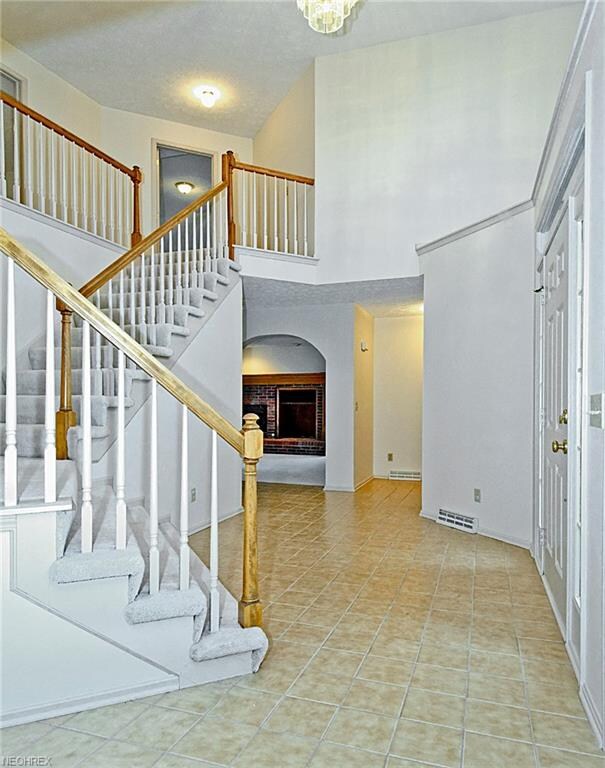 Foyer viewed to south  Family room with brick fireplace  Short hallway to laundry room and 2-car garage  Half-bath to right of hallway.