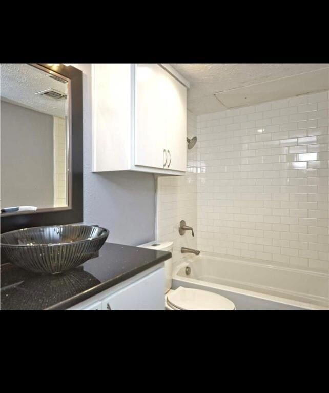 Bathroom with shower / tub combination, a textured ceiling, and vanity