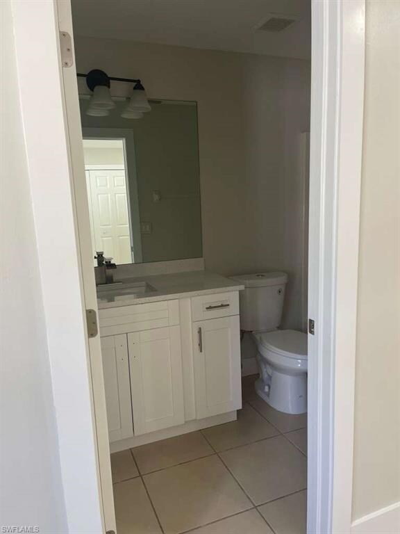 Half bath with light tile patterned floors and vanity