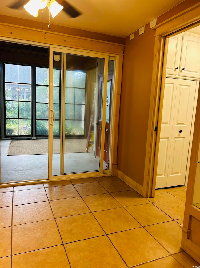 Doorway featuring tile patterned flooring and ceiling fan