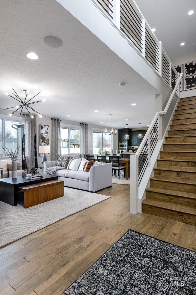 Living room with a chandelier, light wood-style flooring, a textured ceiling, recessed lighting, and stairway