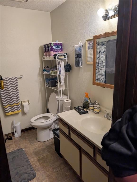 Full bathroom with a textured wall, vanity, a shower with curtain, a textured ceiling, and stone finish flooring