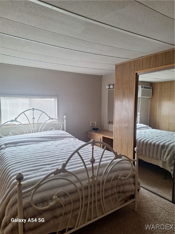 Carpeted bedroom with wood walls and a wall mounte