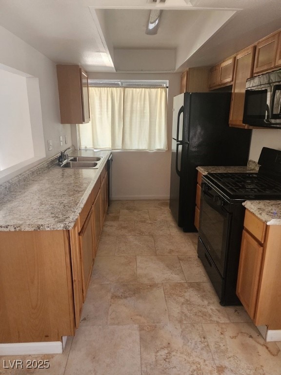 Kitchen featuring black appliances, a sink, stone