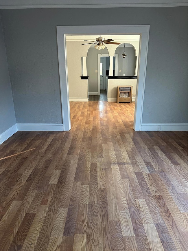 Hall featuring arched walkways, wood finished floors, and baseboards