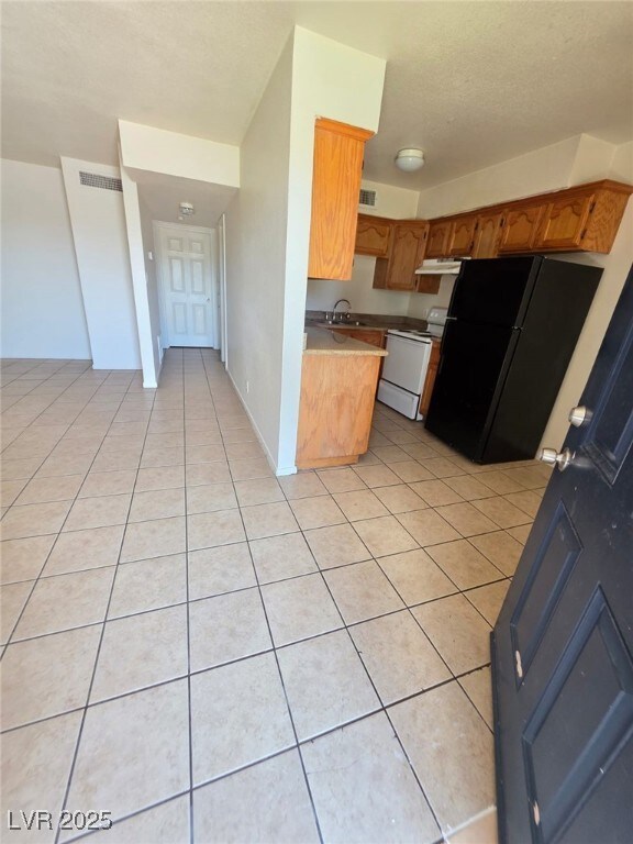Kitchen featuring electric stove, freestanding ref