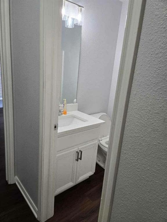 Half bathroom with a textured wall, wood finished