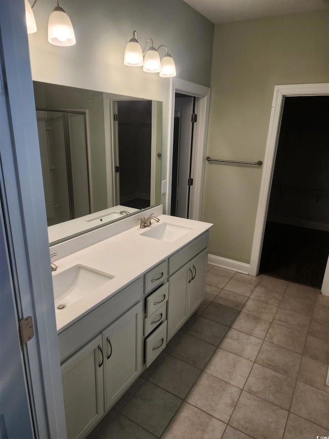 Full bathroom with double vanity, light tile patterned floors, and a shower stall