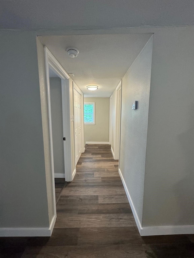 Hallway with baseboards and dark wood-style flooring