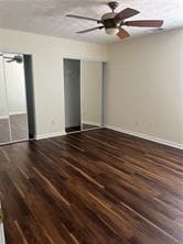 Unfurnished bedroom featuring multiple closets, ceiling fan, and dark wood finished floors