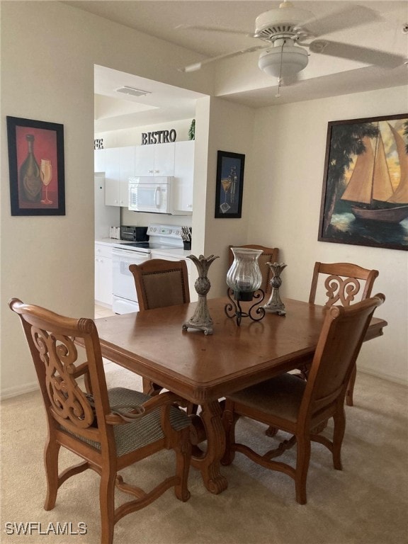 Dining area with light colored carpet and a ceiling fan