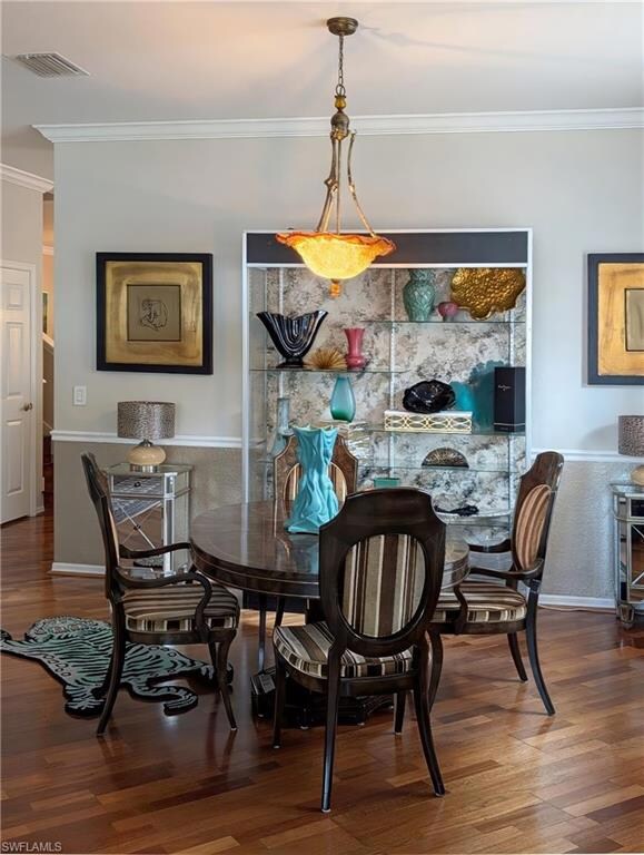Dining space with crown molding and wood finished floors