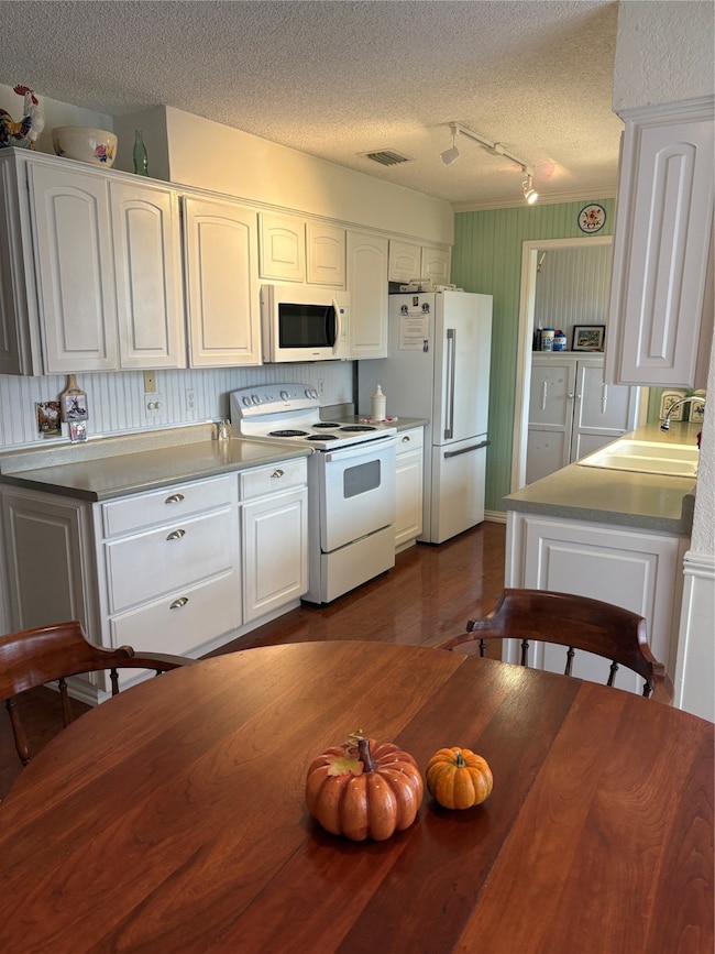 Kitchen featuring white range with electric stovetop, white cabinets, light countertops, a textured ceiling, and fridge