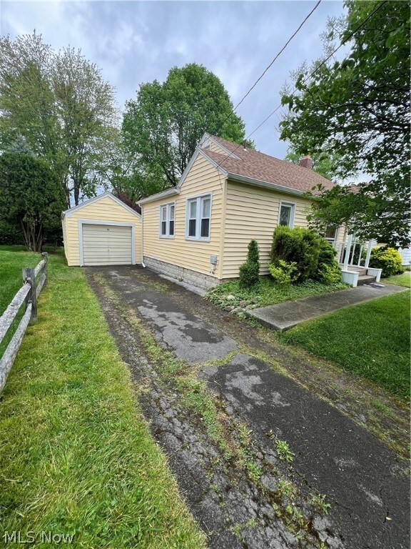 View of front of house featuring a garage, a front yard, and an outdoor structure