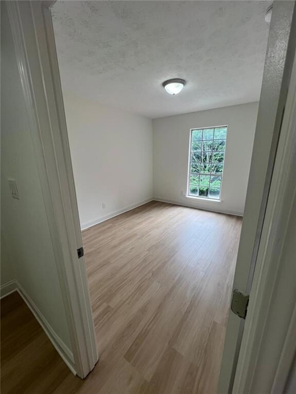 Spare room featuring a textured ceiling, wood finished floors, and baseboards