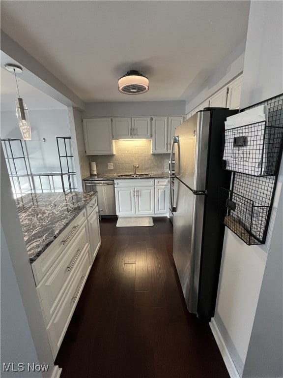 Kitchen with pendant lighting, tasteful backsplash, white cabinets, and appliances with stainless steel finishes