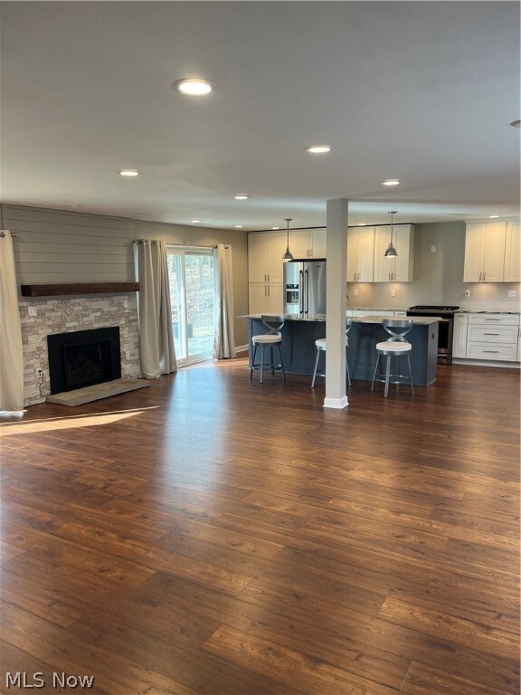  living room featuring dark hardwood / wood-style flooring and a stone fireplace