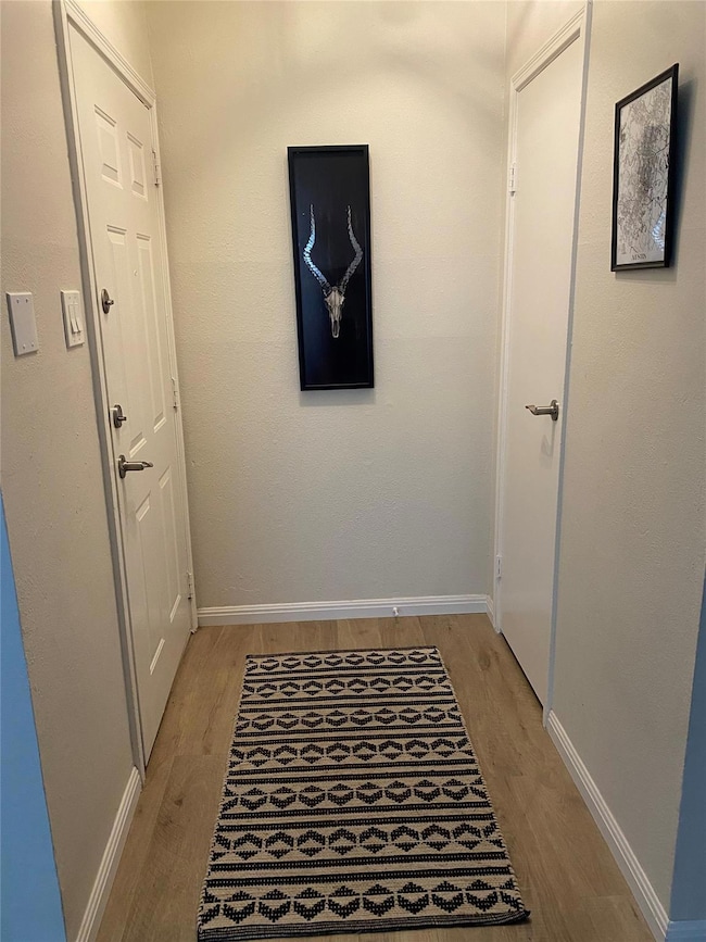 Hallway with baseboards and light wood finished f