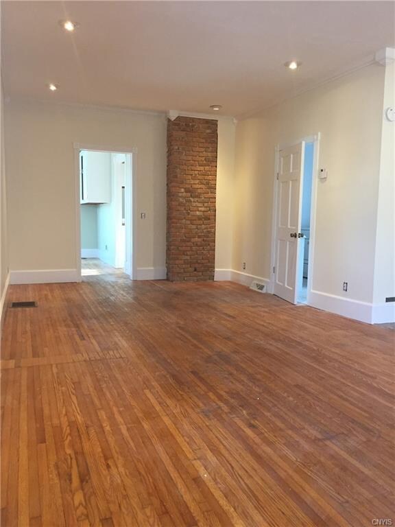 spacious living room with exposed brick and door g