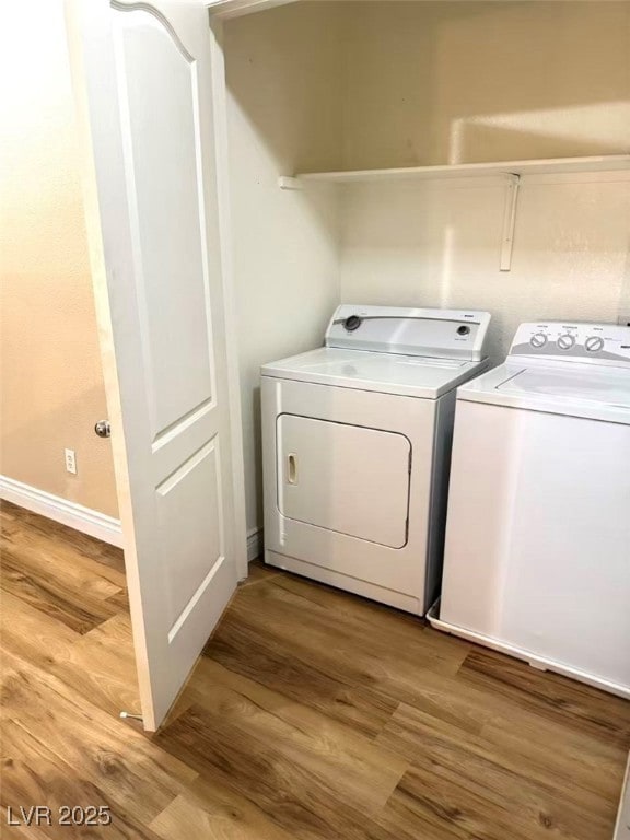 Laundry area with wood finished floors and separate washer and dryer