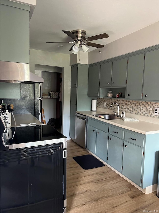 Kitchen featuring light wood-type flooring, light countertops, exhaust hood, and a ceiling fan