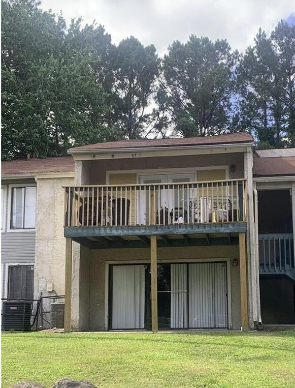 Rear view of property with a balcony, a lawn, and central air condition unit