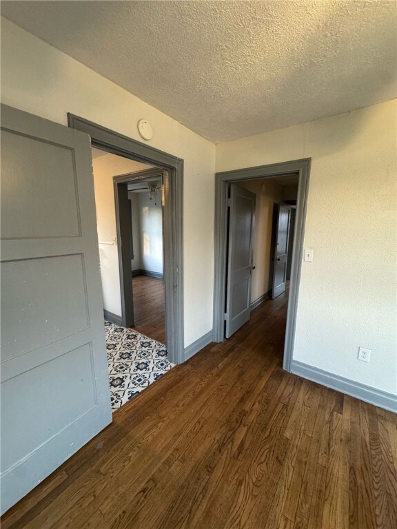 Hall with a textured ceiling and dark hardwood / w