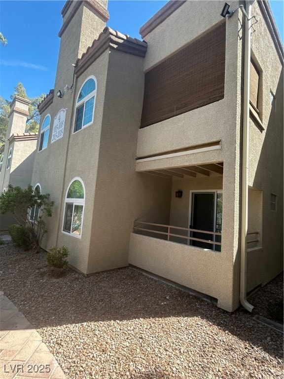 Back of property featuring a chimney, stucco siding, and a patio area